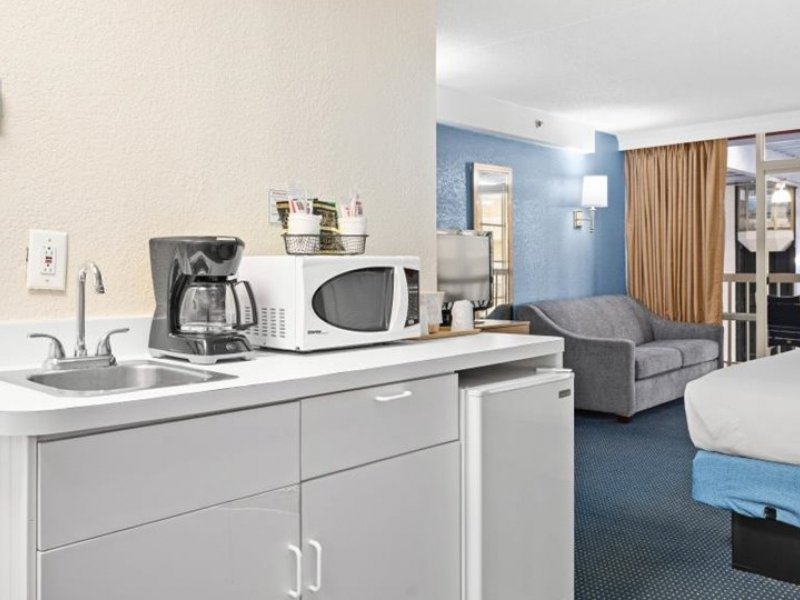 a hotel room with a kitchenette, sink and living area