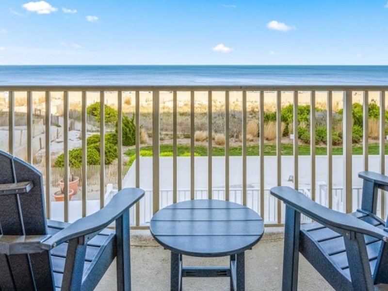 two chairs and a table on a balcony overlooking the ocean