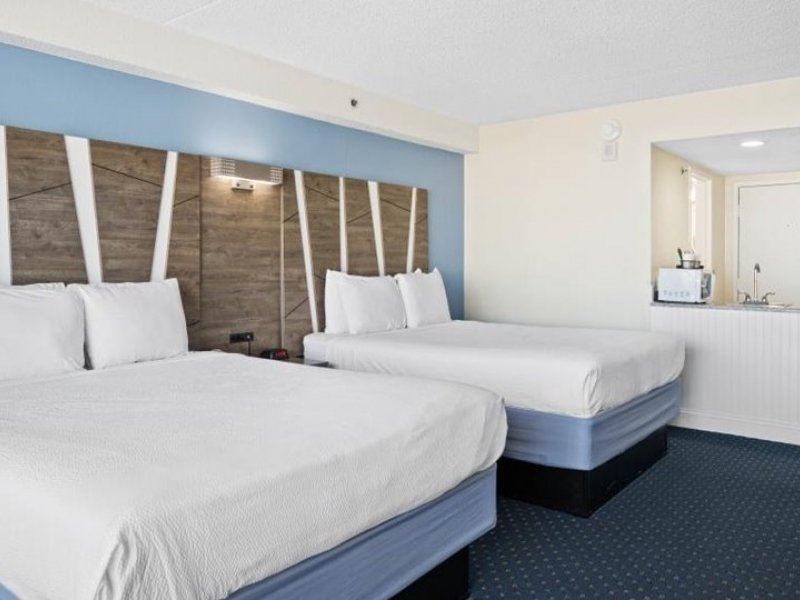 two beds in a hotel room with blue carpet