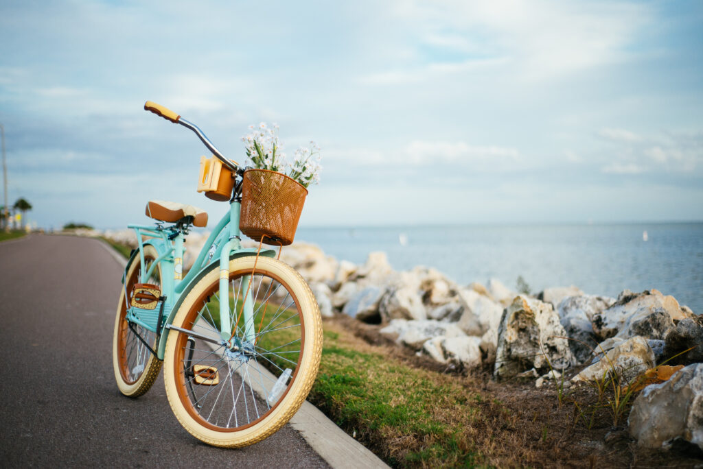a blue bicycle with a basket on the front parked by the water