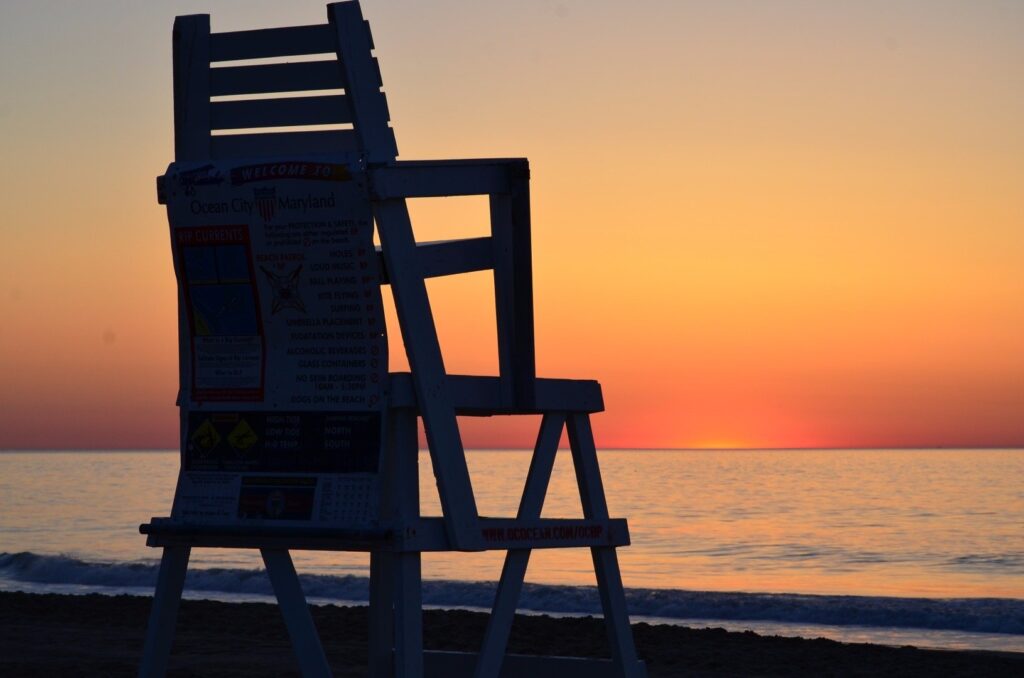 a lifeguard chair sitting on the beach at sunset