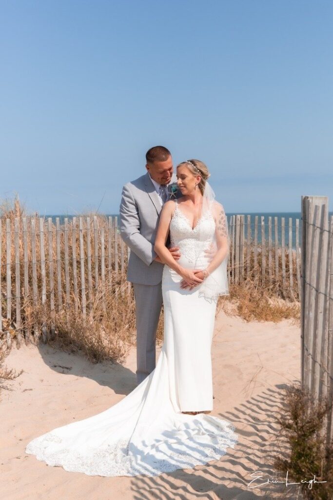 a bride and groom standing on the beach