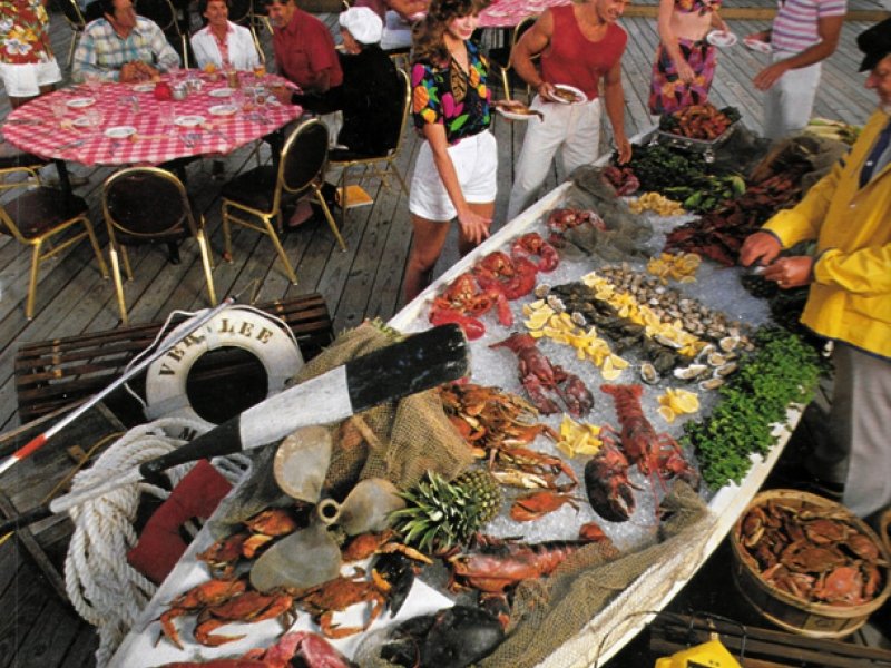 people are standing around a table full of seafood