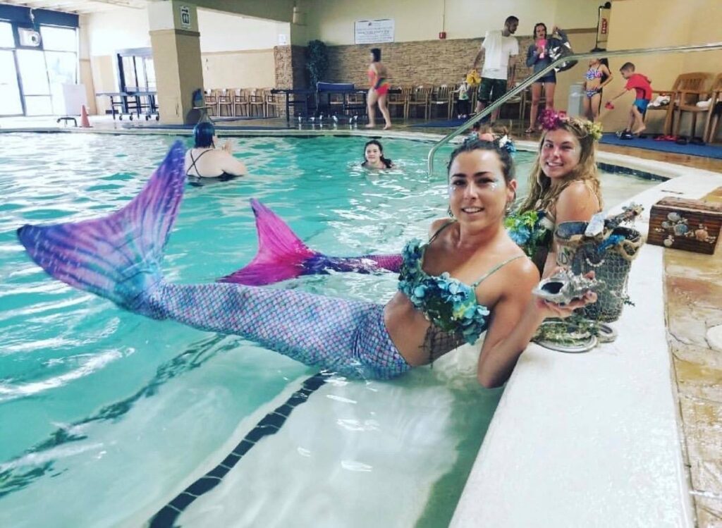 two girls in the pool with mermaid tails