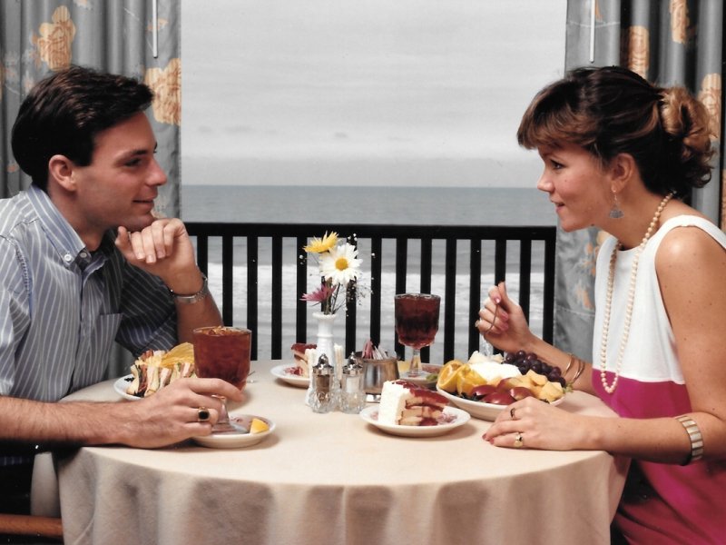 a man and woman sitting at a table with food