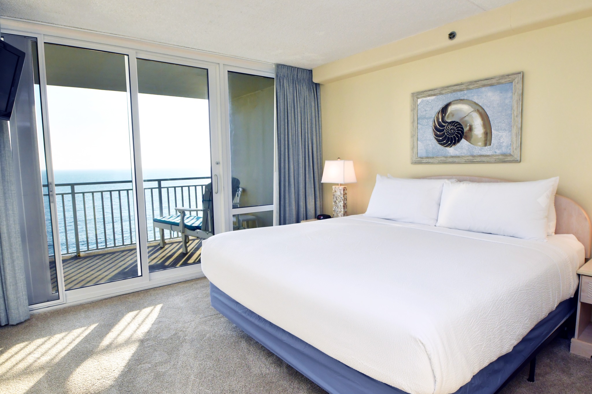 a bedroom with a large bed and balcony overlooking the ocean
