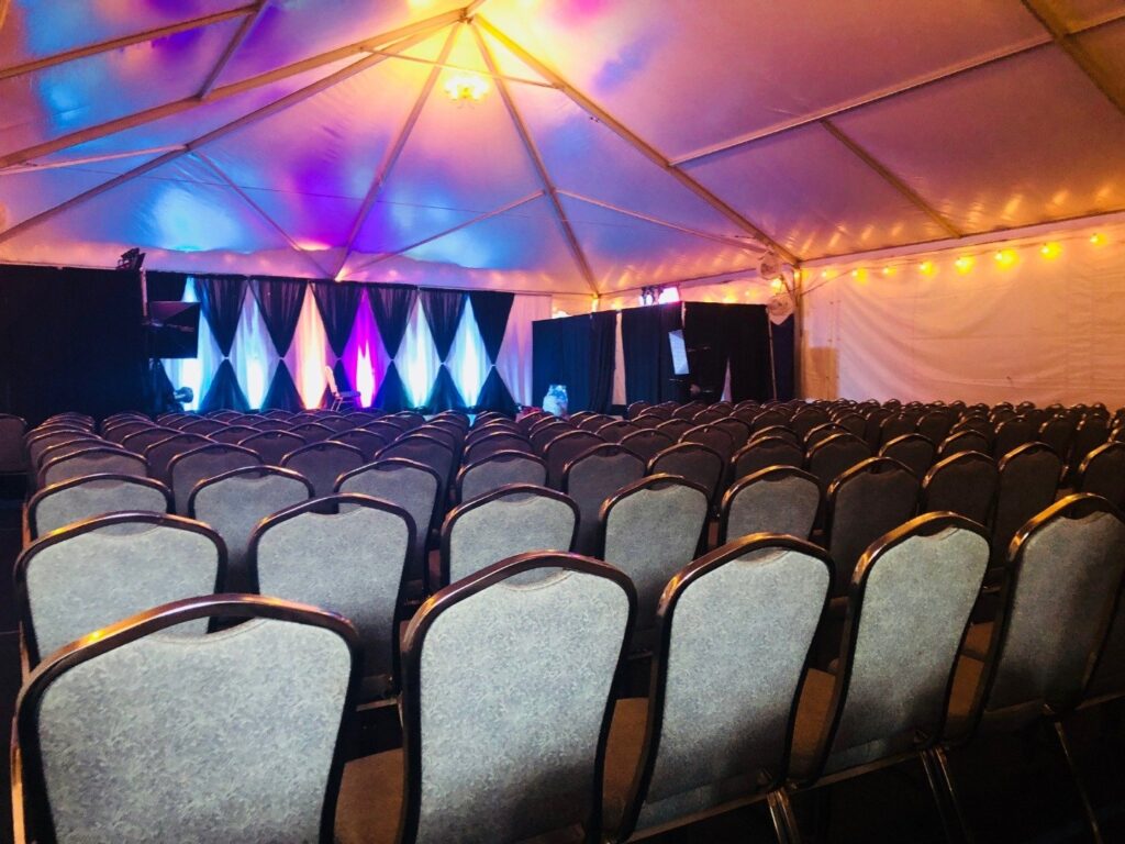 rows of chairs under a tent with lights