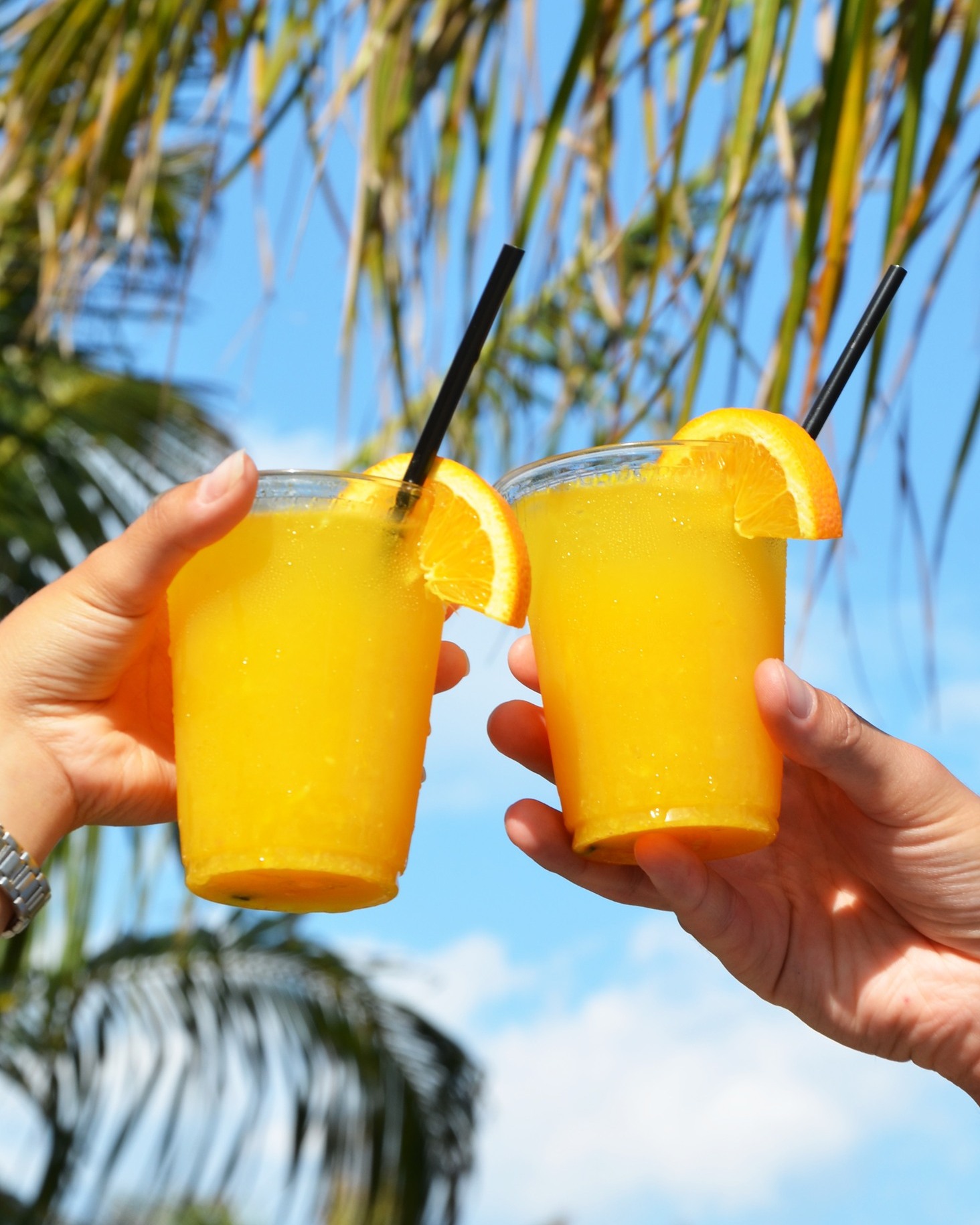 two people holding up glasses with orange juice