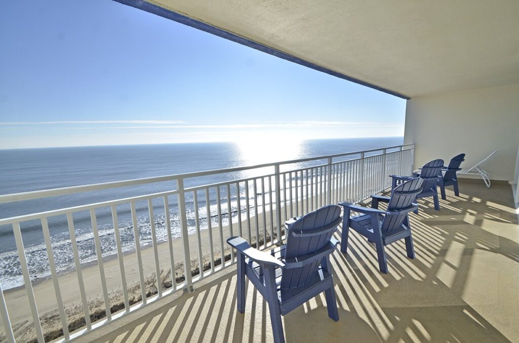 a balcony with blue chairs overlooking the ocean