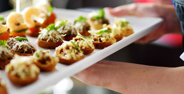 a person holding a tray with small appetizers on it