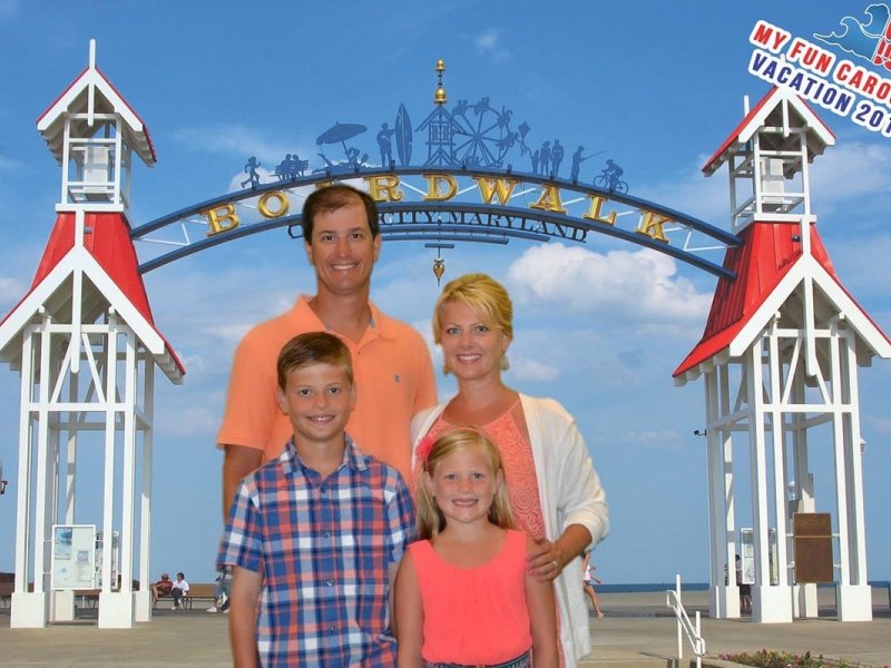a family poses in front of the entrance to an amusement park