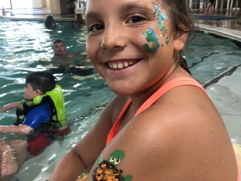 a girl with face paint in a swimming pool