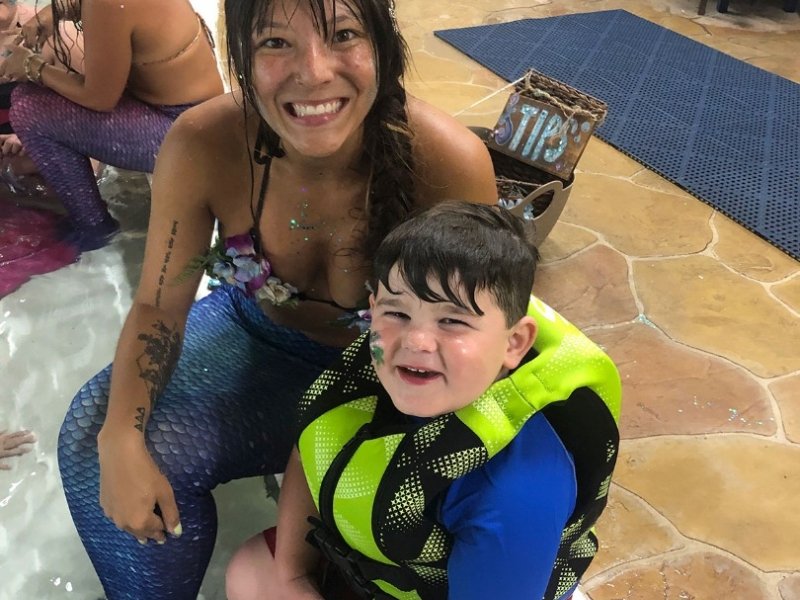 a woman sitting next to a boy in a wet suit