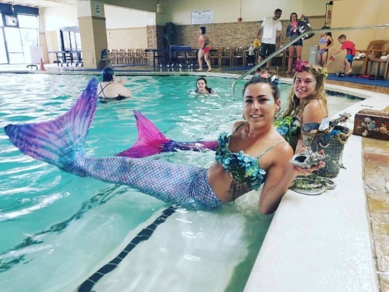 two girls are sitting in the pool with mermaid tails