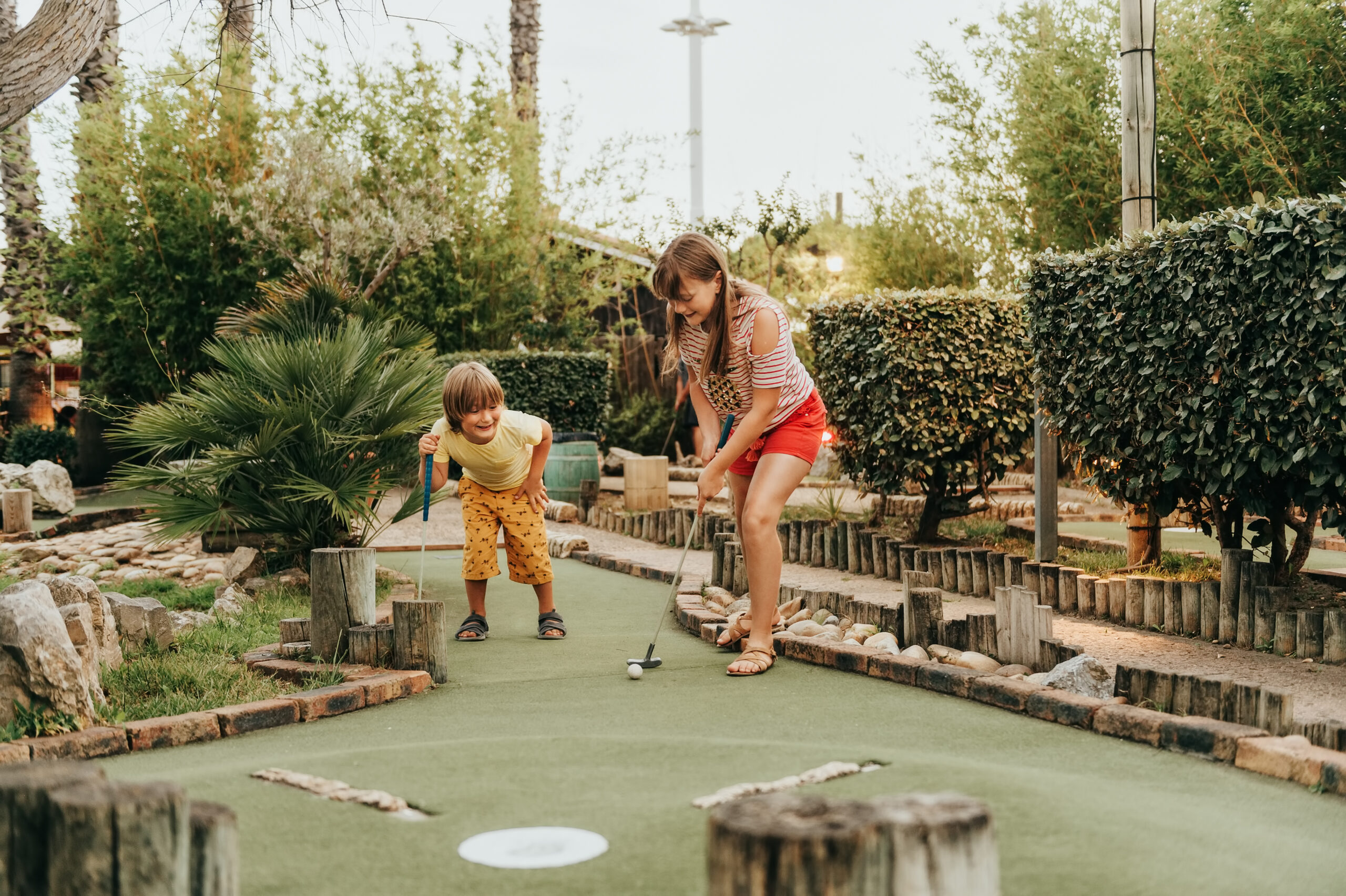 two children playing mini golf in a miniature golf course