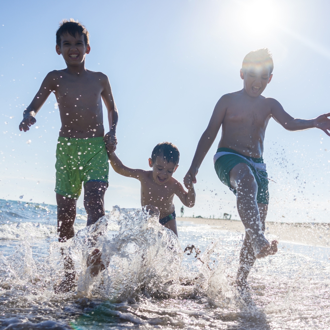 a group of kids running through the water at the beach